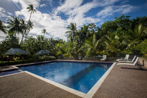 阿洛陶Tawali Leisure & Dive Resort的一个带椅子的游泳池,棕榈树