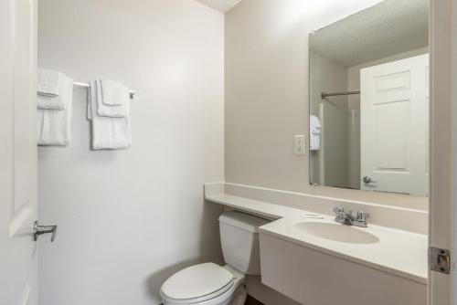 康科德HomeTowne Studios & Suites by Red Roof Charlotte - Concord的一间带卫生间、水槽和镜子的浴室