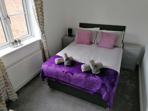 格里姆斯比Agnes House的一间卧室配有一张大床,提供紫色床单和枕头