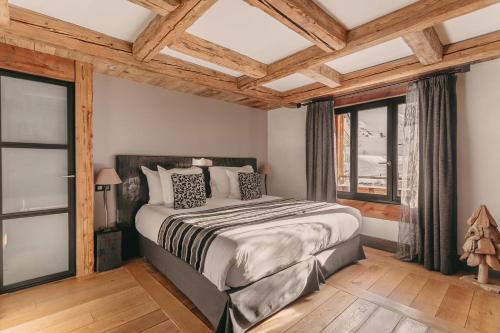 蒂涅Les Suites – Maison Bouvier的一间卧室设有一张大床和窗户。