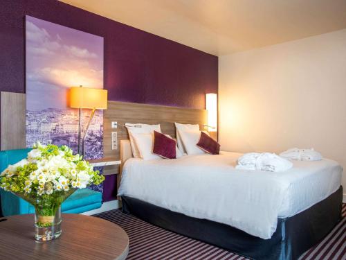 马赛美居马赛中心老城海港酒店的配有床和鲜花桌的酒店客房