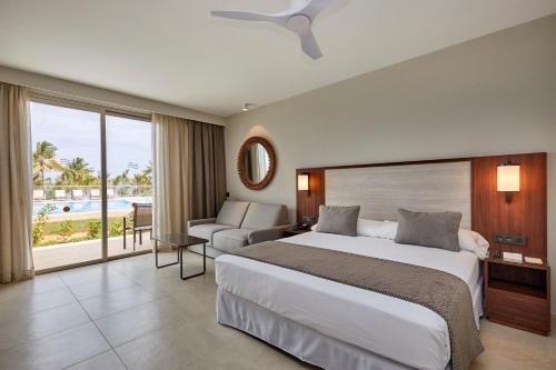 南威Hotel Riu Jambo - All Inclusive的一间卧室设有一张大床,享有游泳池的景色