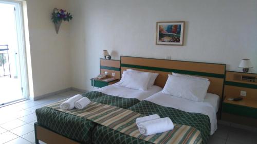 斯卡拉Porto Skala Hotel Village的一间卧室配有一张床,上面有两条毛巾