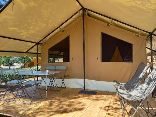 NançayCamping ONLYCAMP LES PINS的木制甲板上的帐篷,配有桌椅