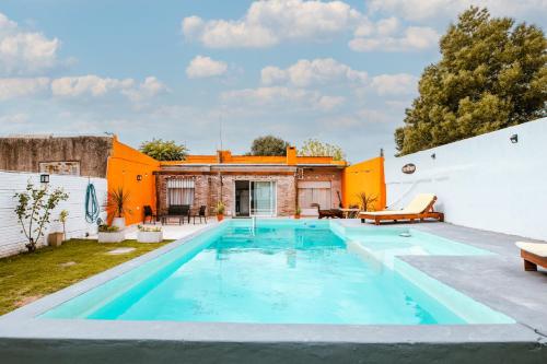坦迪尔El Destino Casa de Descanso的一座室外游泳池,拥有一座橙色和白色的建筑