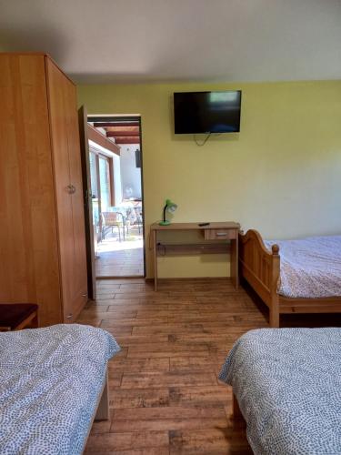 NowogródChata Kurpiowska的一间卧室设有两张床,墙上配有电视。