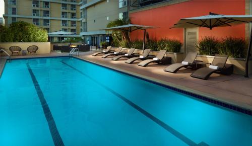 洛杉矶Omni Los Angeles Hotel的一个带椅子和遮阳伞的大型游泳池