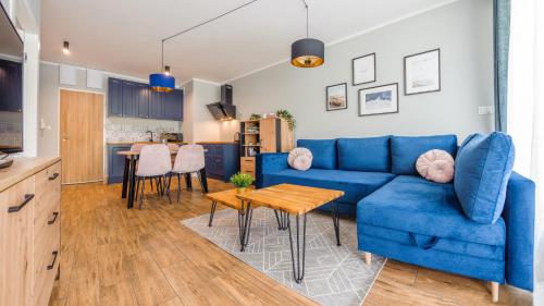 贡斯基Apartamenty Sun & Snow Gąski的客厅配有蓝色的沙发和桌子