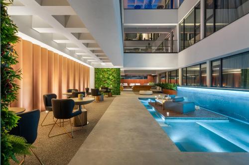 普罗夫迪夫The Emporium Plovdiv - MGALLERY Best Luxury Modern Hotel 2023的酒店大堂设有游泳池和桌椅
