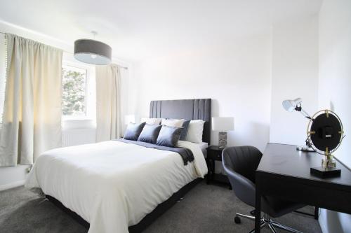 艾尔斯伯里Virexxa Aylesbury Centre - Deluxe Suite - 3Bed House with Free Parking的白色卧室配有床、书桌和椅子