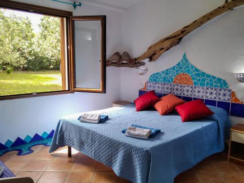 奥罗塞伊Cuccuru Relax - B IUN Q9882的一间卧室配有蓝色的床、红色枕头和窗户