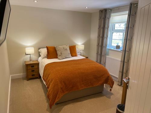 LowickThe Black Bull Inn的一间卧室配有一张带橙色毯子和窗户的床。