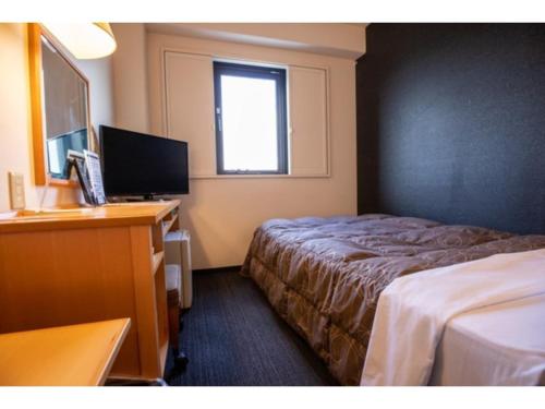 半田AZ INN HANDA INTER - Vacation STAY 69370v的酒店客房配有一张床、一张书桌和一台电视。