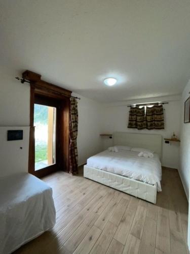 尚波吕克Rifugio Baita Belvedere的卧室配有白色的床,铺有木地板