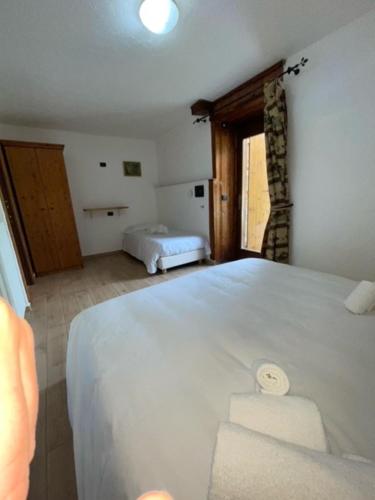 尚波吕克Rifugio Baita Belvedere的卧室设有一张白色大床和一扇窗户。