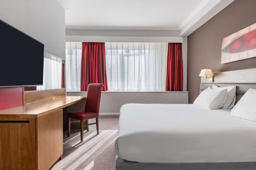 杜伦达勒姆丽笙酒店的酒店客房配有一张床、一张书桌和一台电视。
