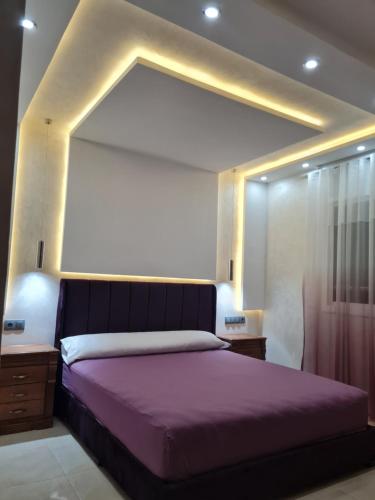 纳祖尔Appartement a Nador的一间卧室配有一张大床和紫色毯子