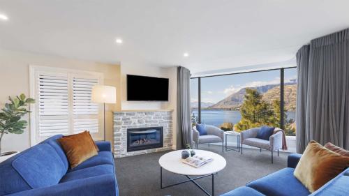 皇后镇Oaks Queenstown Shores Resort的客厅设有蓝色的沙发和壁炉