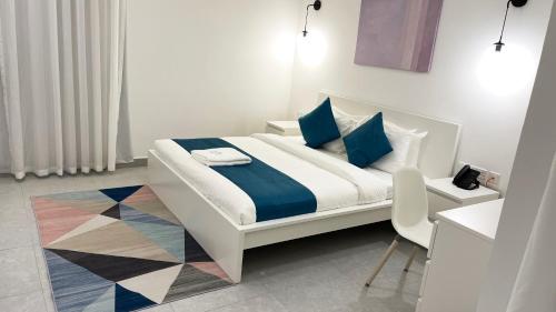 多哈Terminal Inn By Edar City Centre的一张带蓝色枕头的白色床和一把椅子