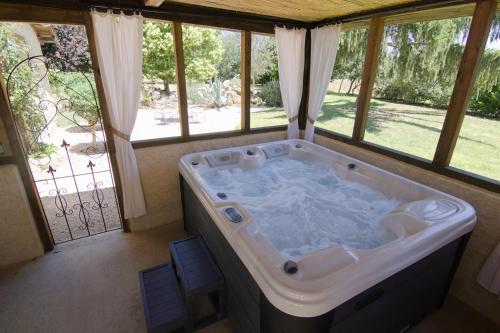 Clermont-PouyguillesAu Bel Air的带窗户的客房内的大浴缸