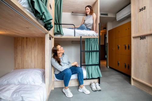 阿姆斯特丹The Bee Hostel的宿舍间的双层床上,有两名女性