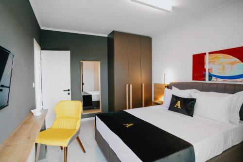 亚历山德鲁波利斯ALEXANDRA Boutique Residence Downtown的一间卧室配有一张大床和一张黄色椅子