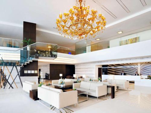 迪拜迪拜阿尔巴沙诺富特酒店的大堂配有白色家具和吊灯。