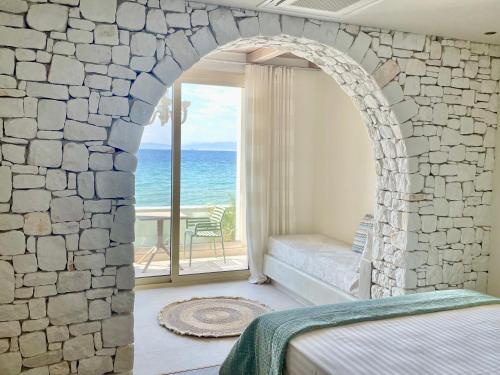 斯卡拉索提罗斯Byblos Aqua-The Sea Front Luxury Villa的一间带石墙和床的卧室,享有海景