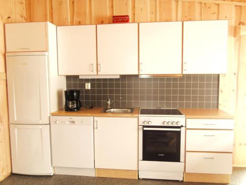 InnfjordenLensmansgarden Fjøsen的厨房配有白色橱柜、炉灶和冰箱。