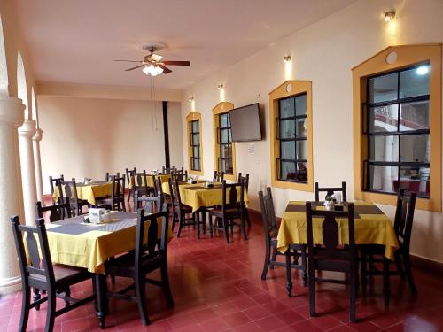 维多利亚城Hotel Los Monteros的餐厅设有黄色桌椅和吊扇