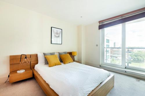 伦敦Beautiful river view close to London Eye的一间卧室配有一张带黄色枕头的床和一扇窗户