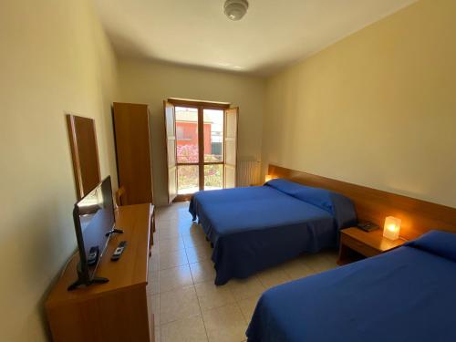 Castelluccio InferioreHotel Mercure的酒店客房设有两张床和电视。