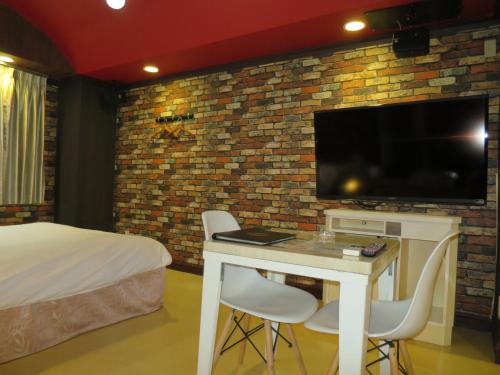 丰山Mio.ap的客房设有一张床和一张桌子及电视