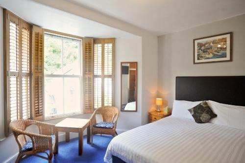 波尔佩罗Penryn House Hotel的卧室配有一张床和一张桌子及椅子