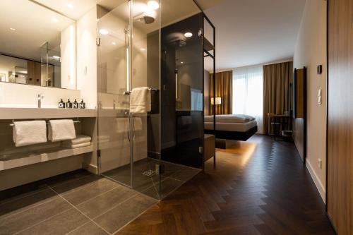 柏林GINN City & Lounge Yorck Berlin的一间带玻璃淋浴的浴室和一张床