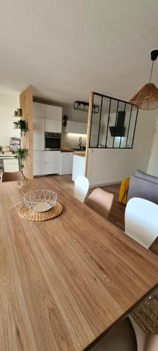 蒙彼利埃Appartement avec terrasse, parking et proche tramway的一间带木桌的客厅和一间厨房