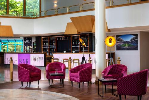 布雷纳乡村公园酒店的大堂设有粉红色的椅子和酒吧