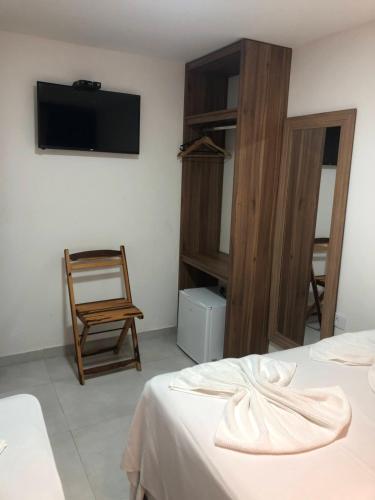 马拉戈日POUSADA MARITIMAR的客房设有两张床、一把椅子和电视。