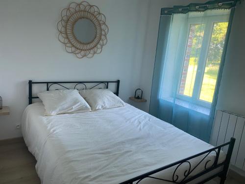 Le gîte des Grivots的一间卧室配有一张带白色床单和镜子的床