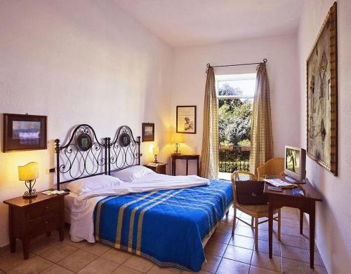 伊斯基亚玛丽亚别墅酒店的一间卧室配有一张床、一张书桌和一个窗户。