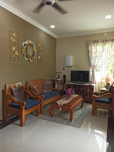 淡马鲁Darney's Homestay Kg Bangau Tanjung的客厅配有椅子、桌子和电视