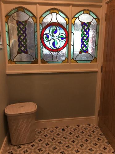 朗德斯通Quayside luxury apt Roundstoneselfcatering的一间有垃圾桶的房间有三扇彩色玻璃窗