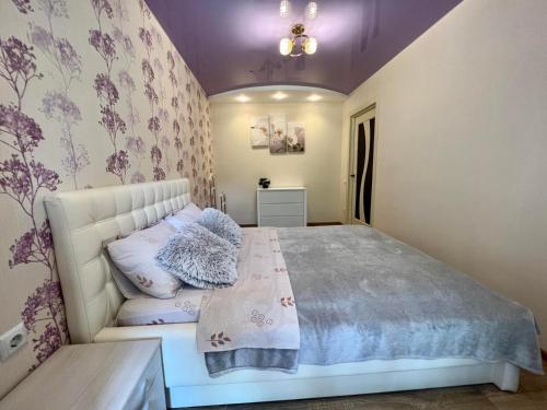 文尼察2-комн ЛЮКС в центре Вишенки的卧室配有白色床和紫色墙壁