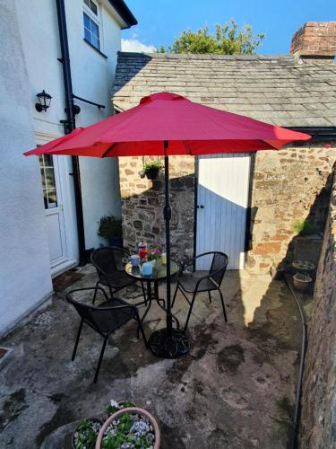 布德Boots Cottage的红色伞下的桌椅