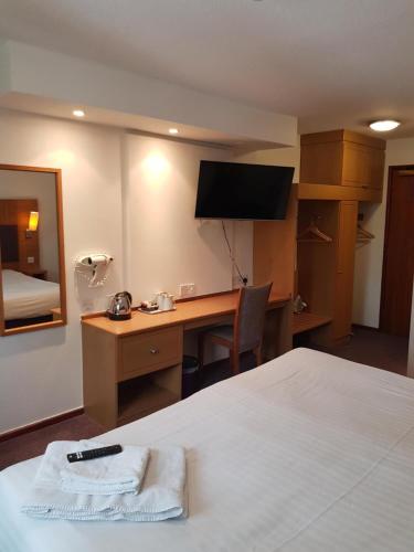 曼彻斯特V Lodge Manchester的酒店客房配有一张床和一张书桌及一台电视