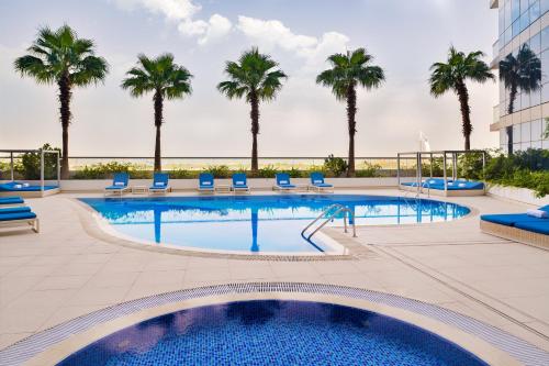 迪拜阿大吉奥高级迪拜阿尔巴沙公寓式酒店的棕榈树酒店后方的游泳池