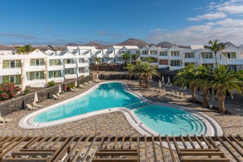 卡门港Apartamentos LIVVO Morromar的一座棕榈树和建筑游泳池