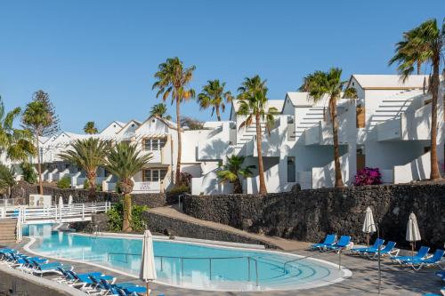 卡门港Apartamentos LIVVO Morromar的一个带椅子和棕榈树的度假游泳池