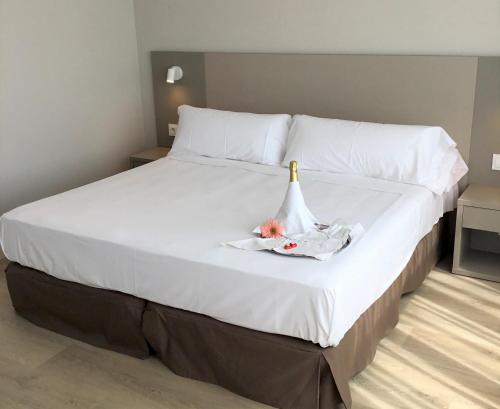 乌特沃雄鹰酒店的一张白色大床,上面有一瓶香槟