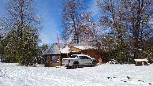 RecintoCabaña Recinto Valle Las Trancas的停在雪地小屋前面的白色卡车